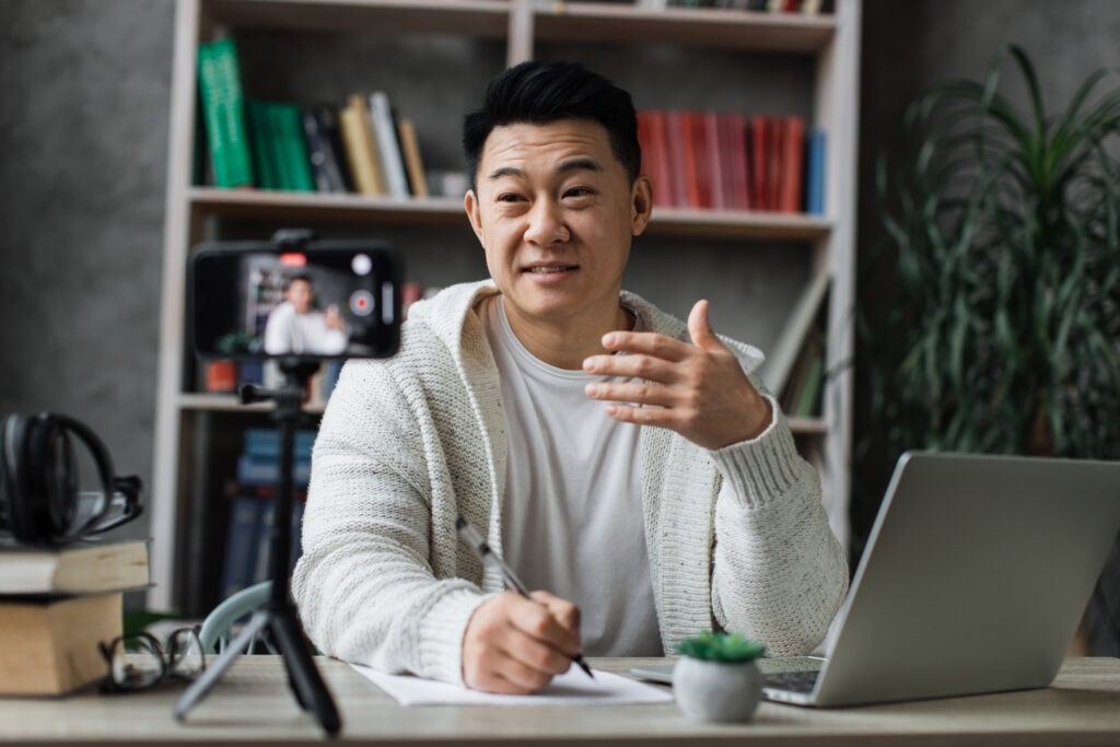 - focus on screen smiling asian man talking and ges 2024 12 13 10 51 51 utc 1 A man sharing on YouTube that his hobby is making YouTube videos, illustrating how to turn hobby into career.
