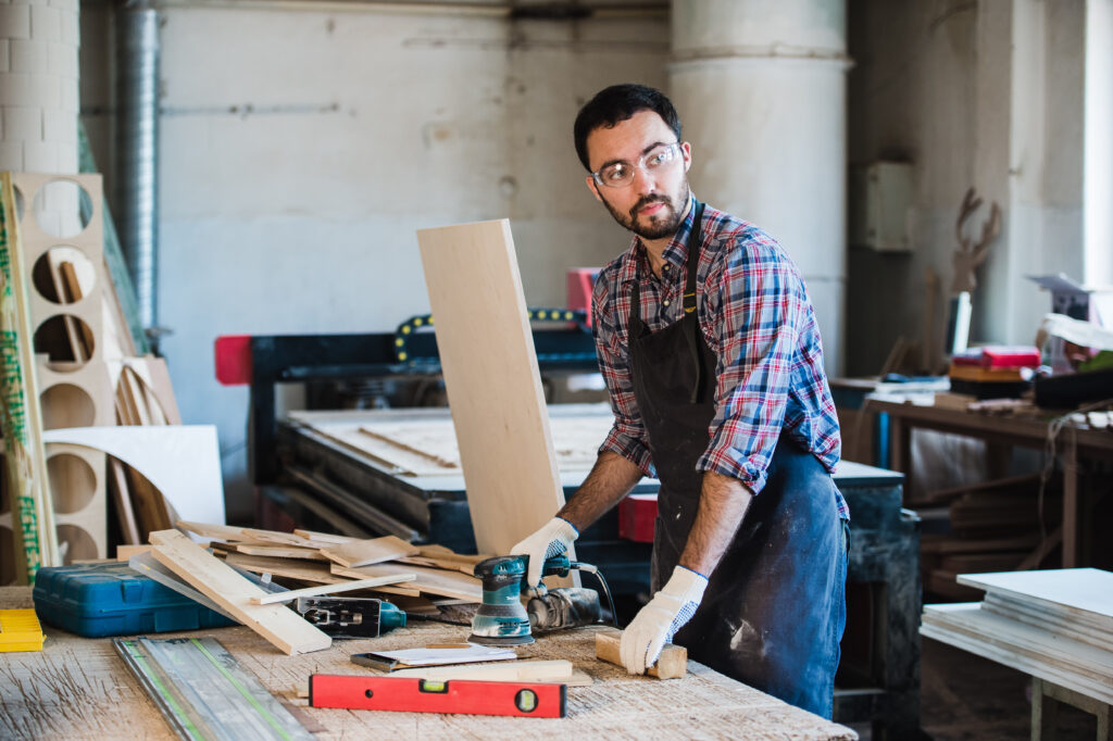 A carpenter using an electric saw to cut wood, representing skilled trades as valuable careers and encouraging parents to stop forcing kids to be doctors or engineers.