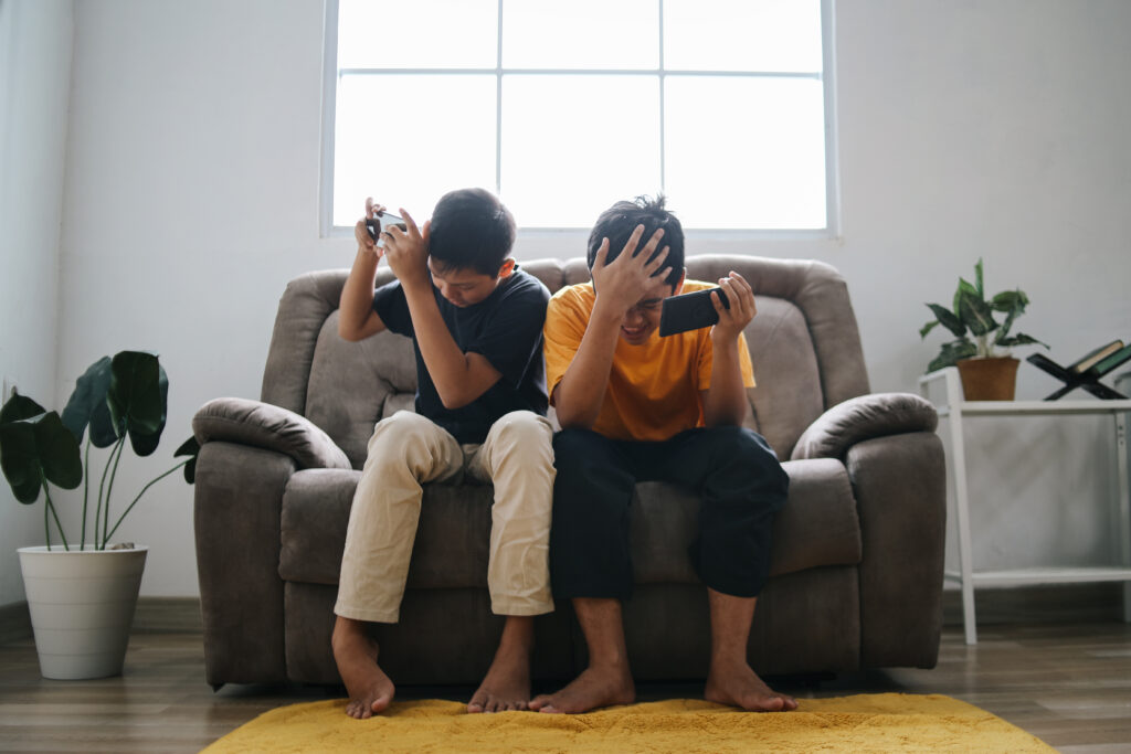 Two boys looking tired and exhausted after playing video games for a long time, showing the effects of excessive screen time on children’s health and energy