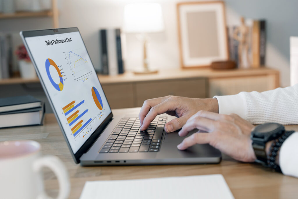 Affiliate marketer working from home analyzing charts and sales data on laptop.