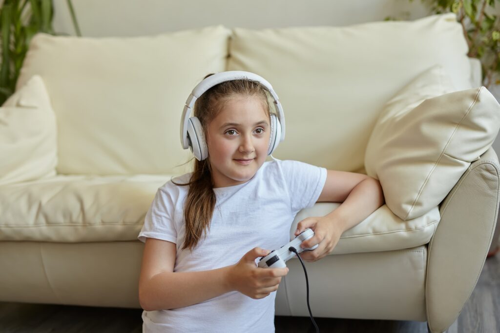 Girl playing video games with headphones, highlighting screen time habits and the need for balanced gaming and outdoor activities for children