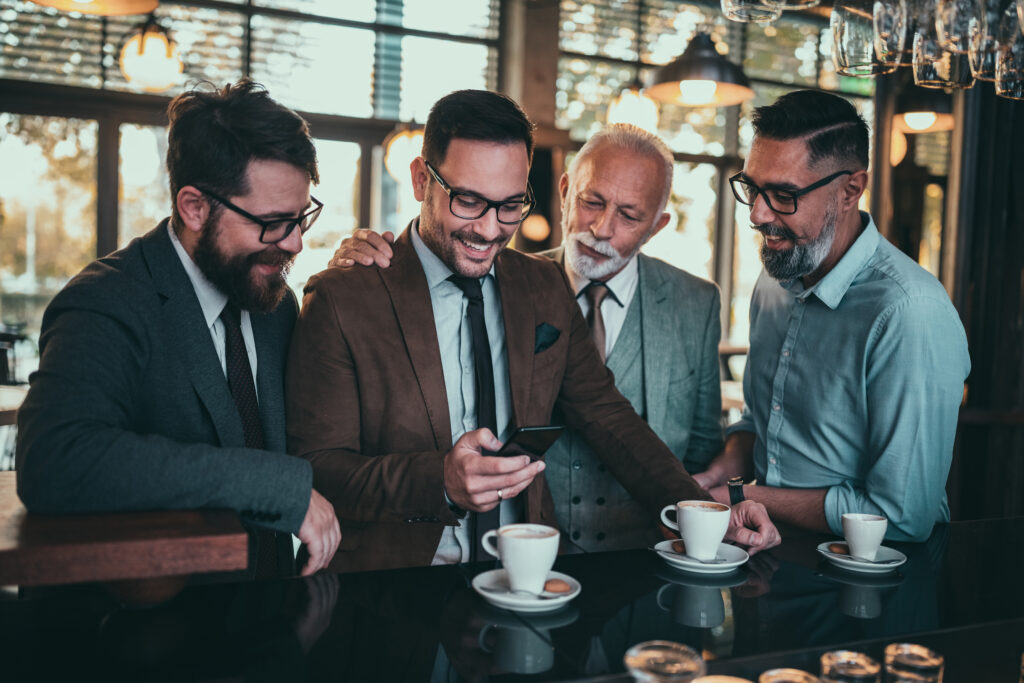Four people standing together and looking at a smartphone, illustrating smartphone addiction and overuse
