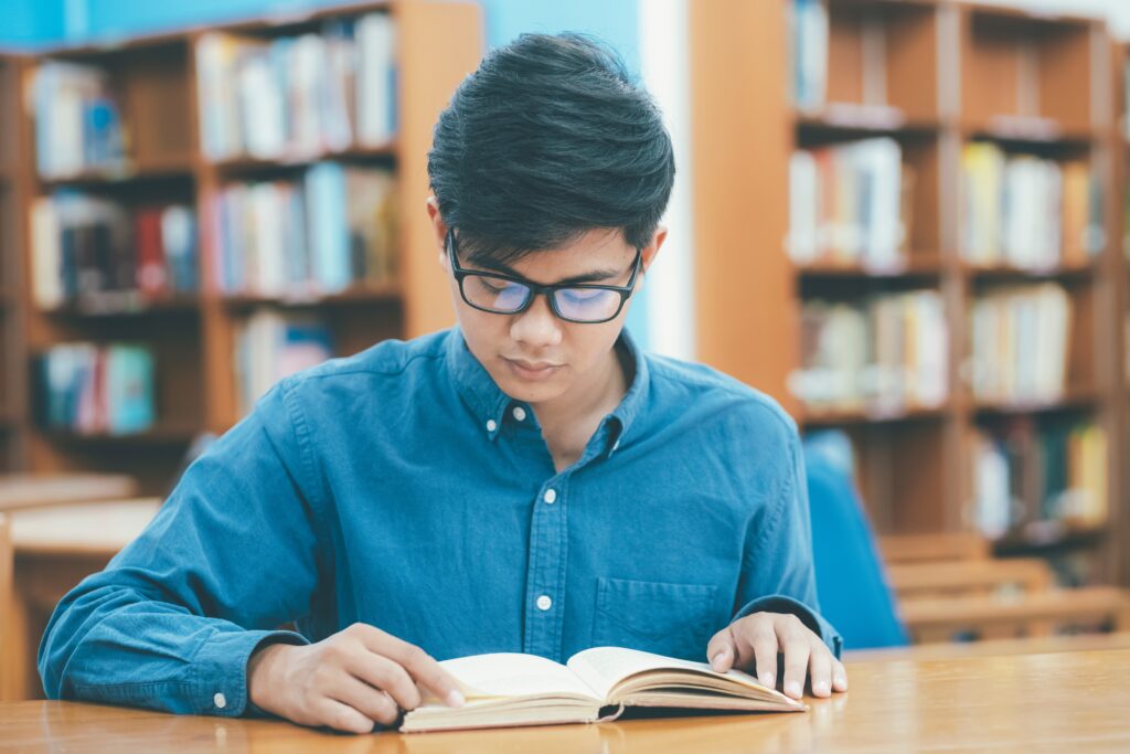 A boy reading a book to learn English and improve his skills.