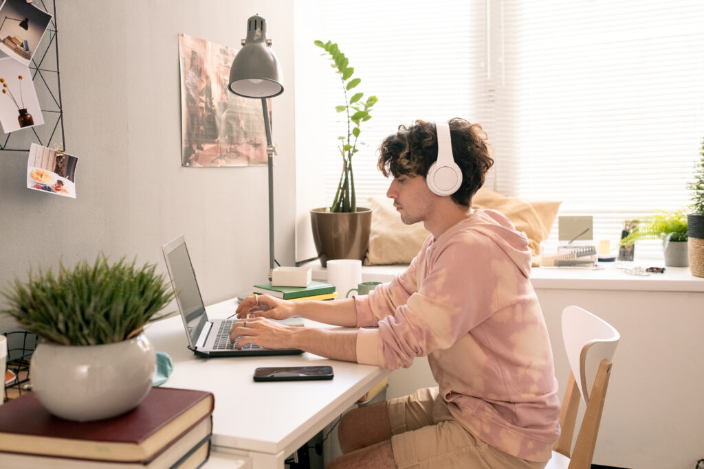 Transcriptionist working from home on laptop with headphones, converting audio to text.