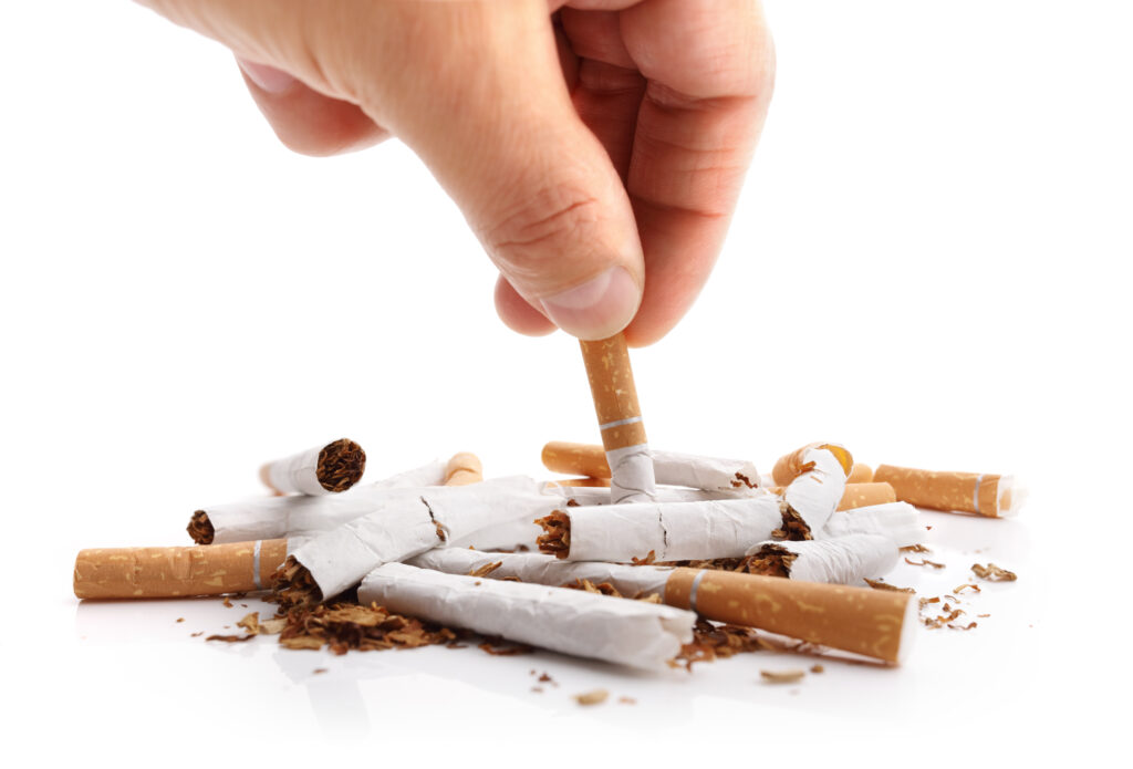 Hand crushing cigarette buds to symbolize quitting smoking and rejecting cigarette smoking.