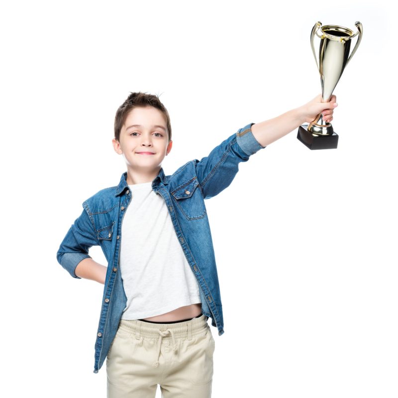Young boy raising a trophy in one hand, celebrating victory